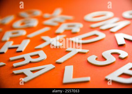 Vista ravvicinata di una pila di lettere piene miste. Concetto educativo su sfondo arancione. Vista ravvicinata pile di lettere miste. Sfondo arancione Foto Stock