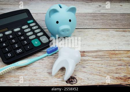 Spazzolino da denti concetto di igiene dentale con calcolatrice e risparmio di maialino su sfondo in legno, denaro dentale e costi di trattamento dentista Foto Stock