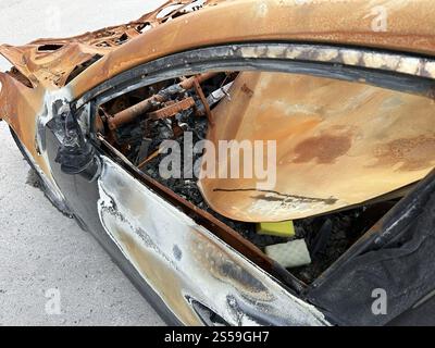 Vista ravvicinata di un'auto gravemente danneggiata dall'incendio, che mostra un'ampia ruggine e distruzione all'interno e all'esterno Foto Stock