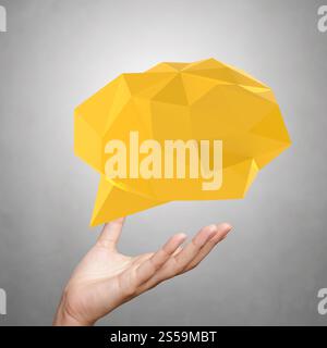 Mano che mostrano una bassa poli geometrica bolla del parlato su sfondo bianco Foto Stock