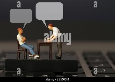 lavorare online capo di un uomo d'affari in miniatura, arrabbiato con il dipendente su un computer portatile con un discorso a bolle vuote Foto Stock