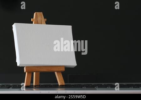 Tela vuota e il cavalletto in legno sul computer portatile come concetto Foto Stock