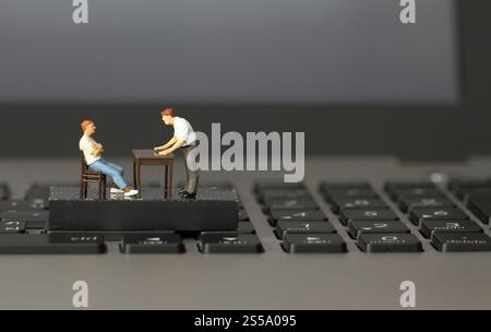 lavorare online in miniatura capo uomo d'affari arrabbiato con il dipendente su un computer portatile Foto Stock