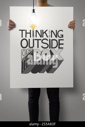 Uomo che mostra un poster di parole disegnate a mano CHE PENSA FUORI DALLA SCATOLA con una lampadina in crescita come concetto Foto Stock