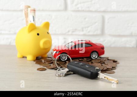 Chiave, modello, salvadanaio e monete su sfondo chiaro Foto Stock