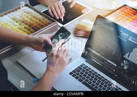 vista dall'alto di due colleghi interior designer che discutono i dati con un diagramma di progettazione sul nuovo schermo di un computer laptop e uno smartphone moderno con un esempio Foto Stock