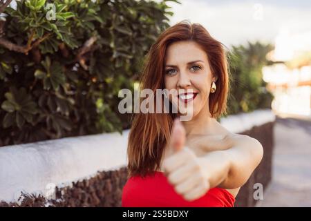 Una donna felice con un vestito rosso sta dando un pollice in su, una foto con spazio di copia. Foto Stock