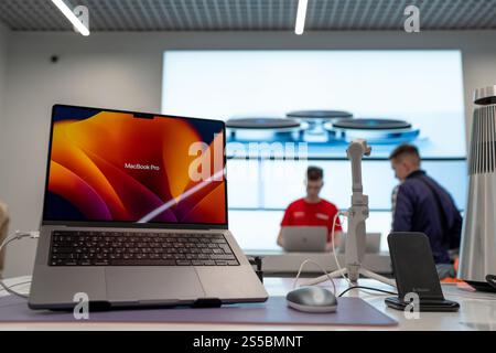 Vista frontale del nuovo potente computer portatile Apple il famosissimo MacBook Pro - clienti che fanno acquisti in background. Minsk, Bielorussia - 24 aprile 2024 Foto Stock