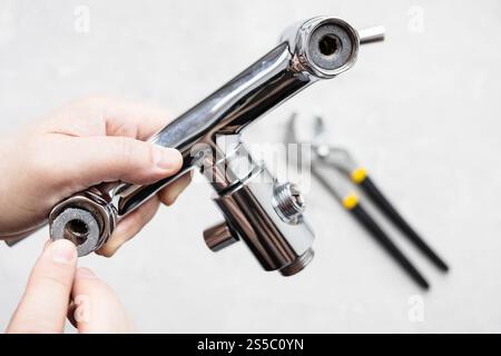 la vista dall'alto dell'idraulico installa la guarnizione in paronite nel chiosco del rubinetto della doccia e la chiave regolabile sul pannello di calcestruzzo sullo sfondo Foto Stock