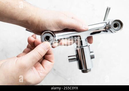 vista dall'alto delle mani di idraulico installare guarnizione di paronite nel rubinetto della doccia e pannello di cemento grigio sullo sfondo Foto Stock