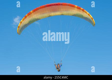 Un colorato parapendio scivola senza sforzo attraverso il cielo. Foto Stock