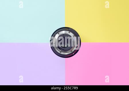 Minimalismo con lente fotografica su sfondo blu, viola, rosa e giallo. Colori pastello alla moda. Vista dall'alto in posizione piatta. Minimalismo con fotografia Foto Stock