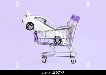 Nuova macchinina bianca nel carrello come simbolo per l'acquisto e il leasing di auto. Concetto di leasing e acquisto di auto. Veicolo nel carrello Foto Stock
