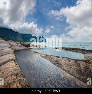 La spiaggia sassosa con bagni di marea a Ersfjord, Senja, Norvegia. Estate giorno polare notte costa. I denti di drago di roccia nel lontano. Foto Stock