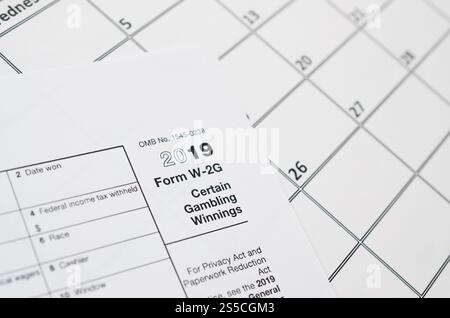 Il modulo IRS vuoto si trova su una pagina di calendario vuota. Concetto del periodo fiscale. Copia spazio per il testo. L'IRS forma W-2G il bianco vincente del gioco d'azzardo giace su vuoto Foto Stock