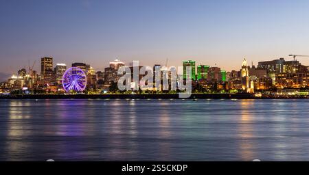 Il vecchio porto di Montreal e lo skyline del centro cittadino di notte. Edifici colorati che si riflettono nell'acqua. Montreal, Quebec, Canada. Foto Stock