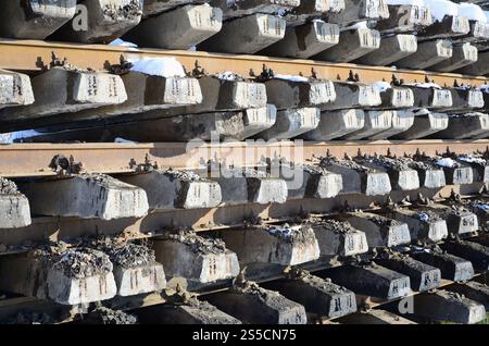 Molti vecchi binari e traversine sono impilati in un magazzino ferroviario in inverno. Il concetto di rinnovamento di una ferrovia logora Foto Stock