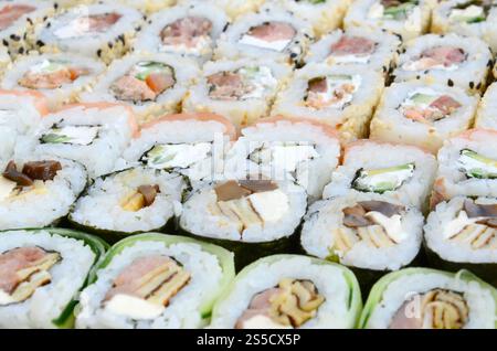 Primo piano di un sacco di sushi roll con diversi ripieni. Macrofo di cucina classica giapponese cotta. Immagine di sfondo Foto Stock