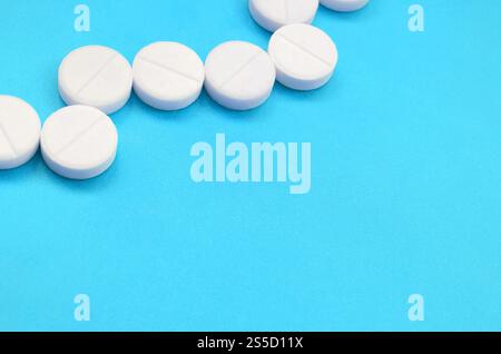 Un paio di compresse bianche giacciono su un blu brillante superficie di sfondo. Immagine di sfondo sul farmaceutico e medico, argomenti Foto Stock