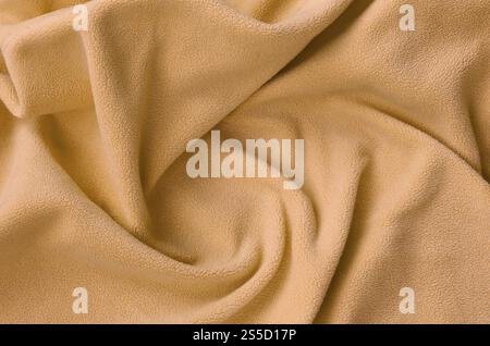 La coperta di pelliccia arancione in tessuto di pile. Uno sfondo di luce arancione peluche morbido materiale in vello con un sacco di pieghe in rilievo Foto Stock