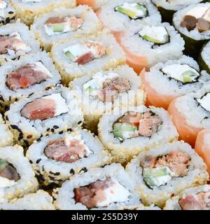 Primo piano di un sacco di sushi roll con diversi ripieni. Macrofo di cucina classica giapponese cotta. Immagine di sfondo Foto Stock