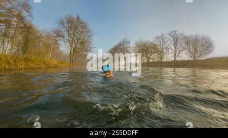 Solitaria donna selvaggia nuotata al primo semaforo in un freddo giorno invernale nebbioso. REGNO UNITO Foto Stock