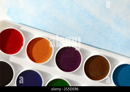 Una nuova serie di acquerelli si trova su un foglio di carta, che mostra un disegno astratto ad acquerello sotto forma di tratti blu. Il concetto di amatoriale Foto Stock