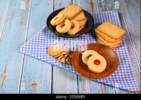 Impilare molti tipi di biscotti su un piatto e metterli su un tavolo di legno. Foto Stock