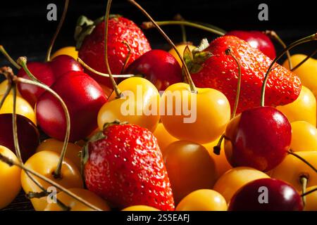 fragole miste di ciliegie su sfondo nero Foto Stock