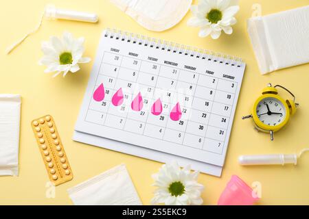 Composizione piatta con calendario e prodotti mestruali su sfondo beige Foto Stock