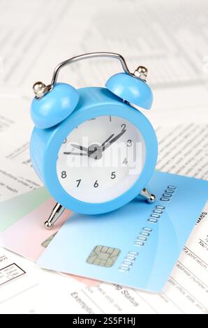 1040 modulo di dichiarazione dei redditi individuali con sveglia blu sulle carte di credito. Concetto di periodo fiscale negli Stati Uniti. 1040 imposta sul reddito individuale Foto Stock