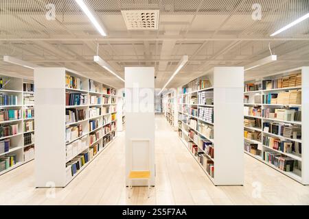 Moderno interno biblioteca con scaffali bianchi, libri organizzati e illuminazione luminosa, la biblioteca universitaria di Helsinki, Finlandia Foto Stock