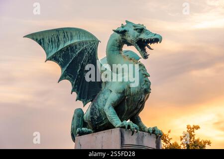 Una statua di drago verde con ali allungate contro un cielo crepuscolo sul Ponte del Drago a Lubiana, Slovenia Foto Stock
