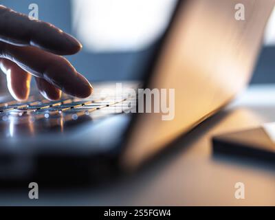 Uomo che lavora online sul suo computer portatile con la luce del sole che entra dalla finestra Foto Stock