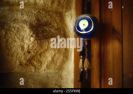 Un amuleto decorativo tradizionale, il malocchio turco o nazar boncuğu, è appeso davanti alla porta della casa per protezione e simbolo di buona fortuna Foto Stock
