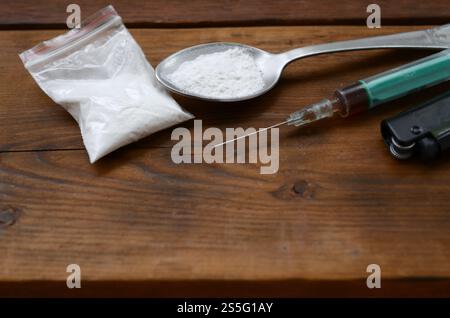 Roba di spacciatori. Siringa, accendino e cucchiaio pieni di polvere bianca su sfondo di legno. Eroina e metanfetamina che usano. Dipendenza da narcotici Foto Stock