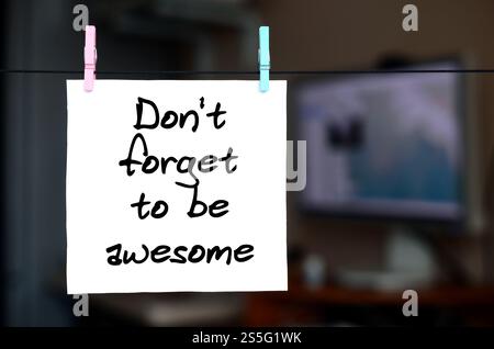 Non dimenticare di essere fantastico. La nota è scritta su un adesivo bianco che si appende con un clothespin su una corda su uno sfondo dell'interno dell'ufficio Foto Stock