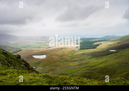 Vista panoramica dell'oceano e delle montagne dal Conor Pass sulla penisola di Dingle in un giorno coperto nella contea di Kerry, Irlanda. Foto Stock