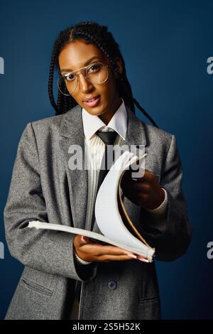 In un ambiente moderno, una giovane donna sfoggia il suo abito elegante mentre legge da un notebook. Foto Stock