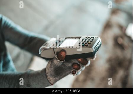Mendicante seduto sotto il cavalcavia con una macchina per carte di credito e carte di credito. Foto Stock