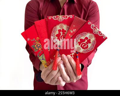 Un uomo asiatico che regge buste rosse cinesi, noto anche come hongbao o angpao. La busta rossa è piena di soldi e famosa per il Capodanno cinese. Foto Stock