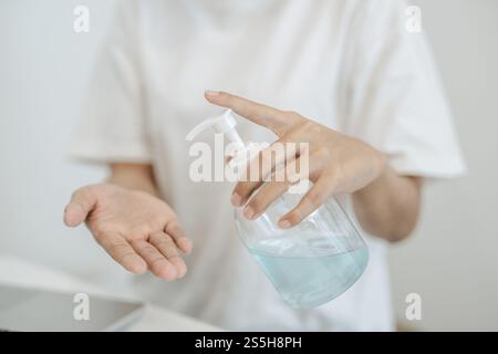 Donne che indossano camicie bianche che premono il gel per lavarsi le mani e pulire le mani. Foto Stock
