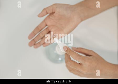 Donne che indossano camicie bianche che premono il gel per lavarsi le mani e pulire le mani. Foto Stock