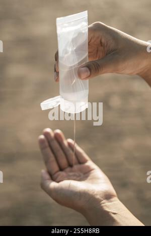 Donne che indossano camicie bianche che premono il gel per lavarsi le mani e pulire le mani. Foto Stock