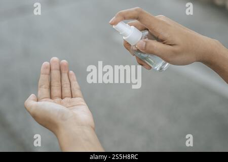 Donne che indossano camicie bianche che premono il gel per lavarsi le mani e pulire le mani. Foto Stock