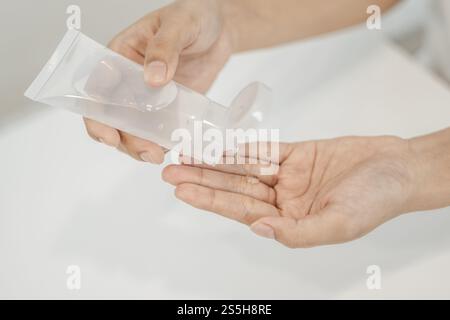 Donne che indossano camicie bianche che premono il gel per lavarsi le mani e pulire le mani. Foto Stock