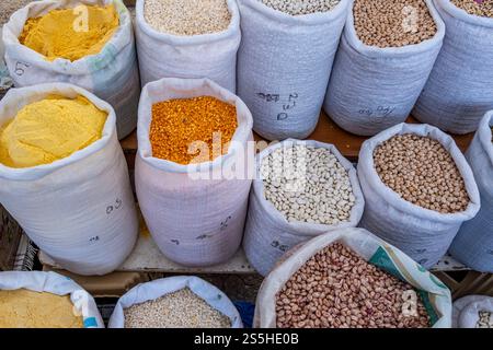 Una varietà di sacchetti di fagioli e altri grani di colore diverso sono esposti su un tavolo. Le borse sono di diverse dimensioni e colori Foto Stock