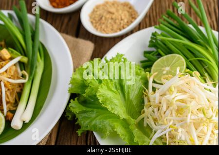 Germogli di soia, insalate, lime e cipolline in piatto bianco su un tavolo di legno Foto Stock
