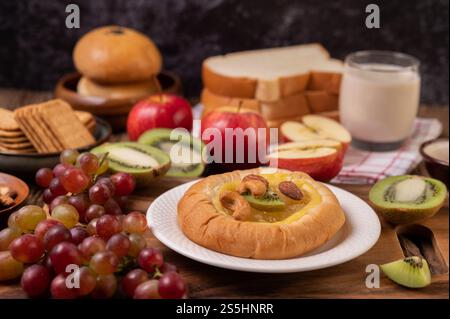 Spalmare il pane con la marmellata e metterlo con kiwi e uva. La mela sul tavolo di legno Foto Stock
