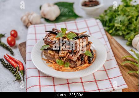 Maiale fritto con cipolla fritta e menta fritta in un piatto bianco. Foto Stock